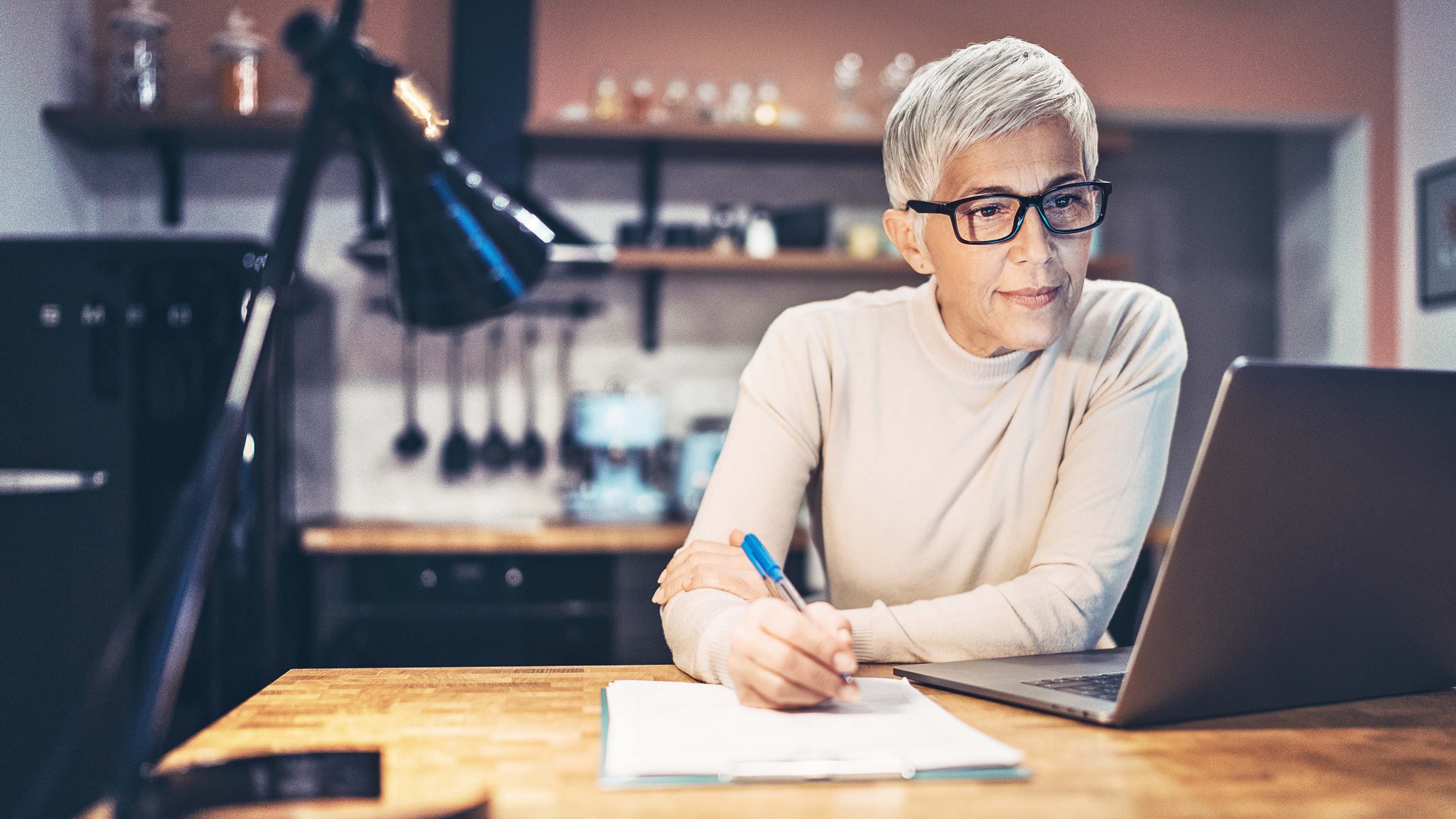 Frau am Laptop und mit Stift in der Hand optimiert ihre Steuern