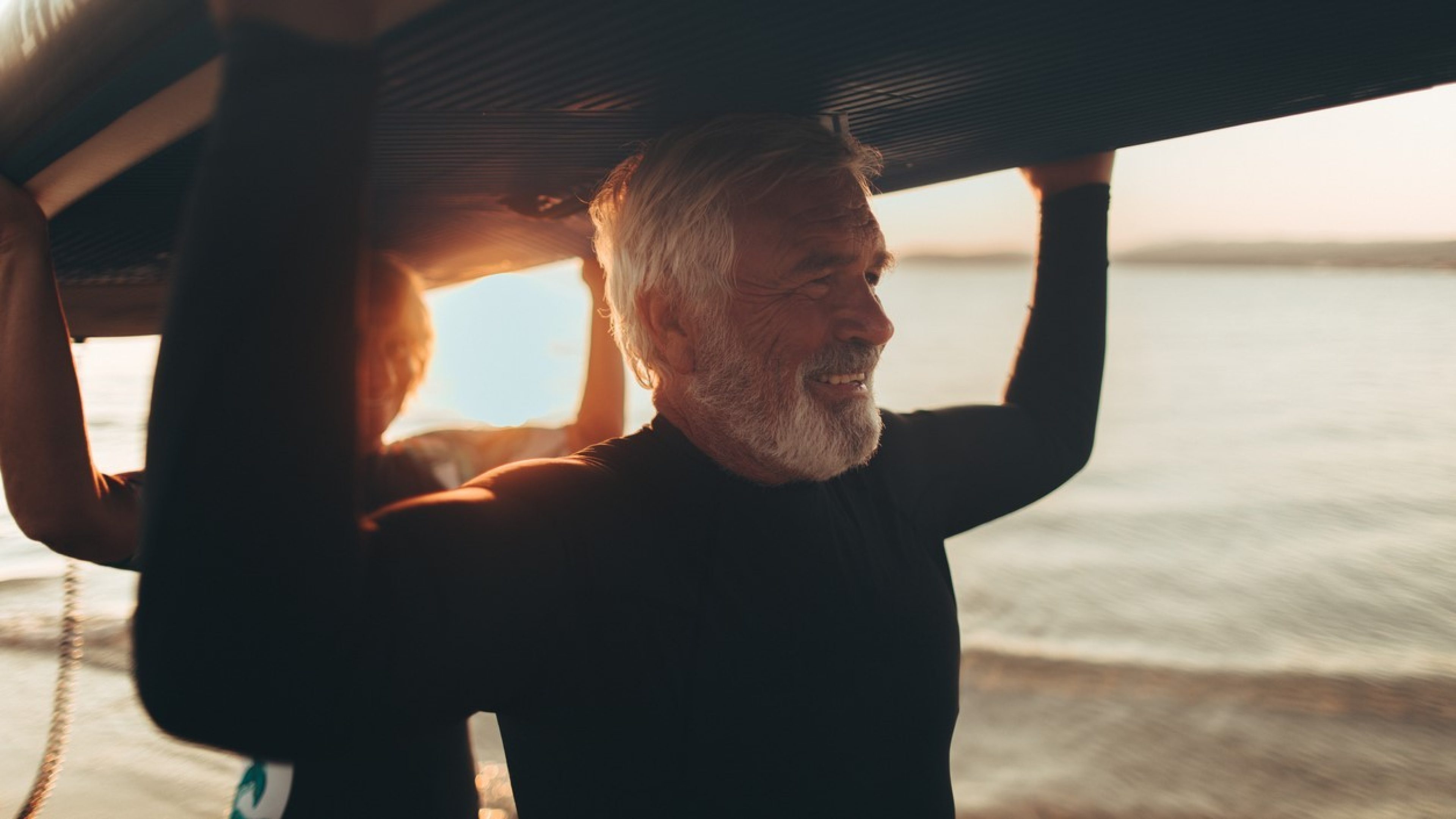 Ein Mann und eine Frau surfen zusammen am Strand, dank ihrer Teilpensionierung.