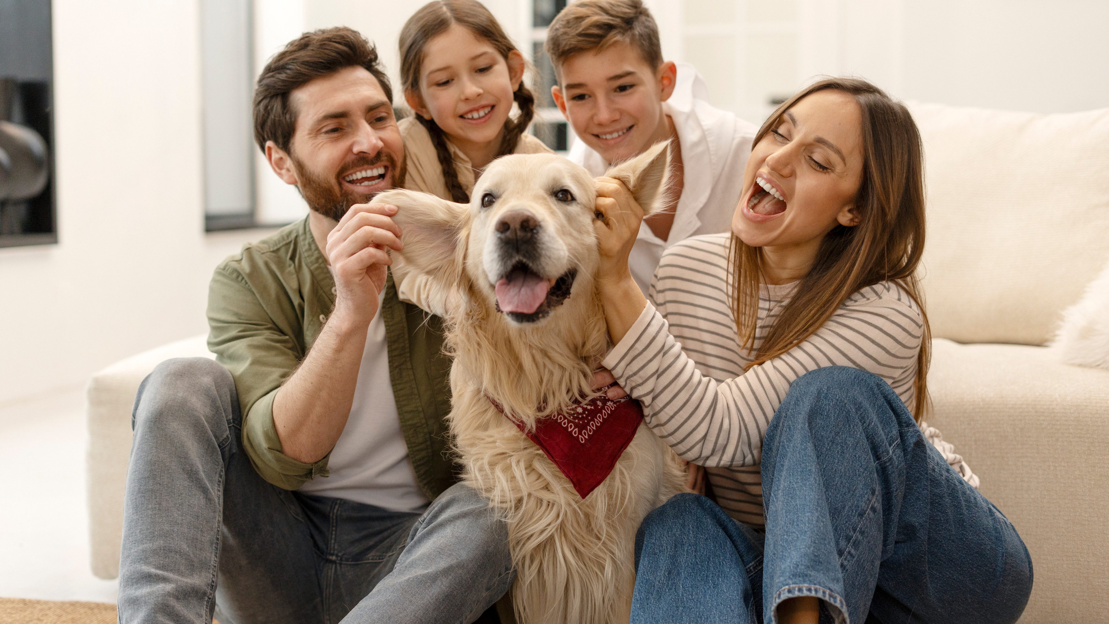 4-löpfige Familie mit Hund sitzend auf dem Boden vor einem Sofa