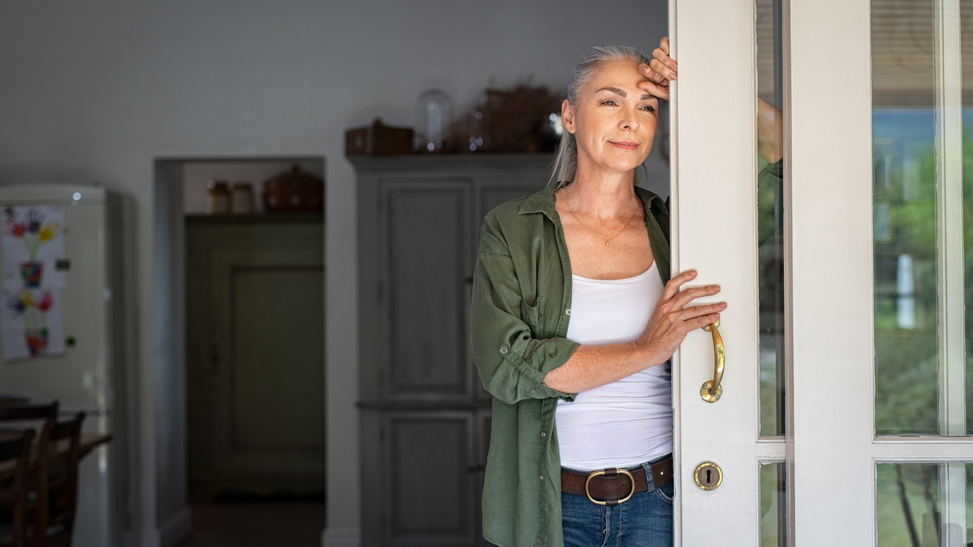 Eine Frau mittleren Alters steht an der Terassentür und schaut heraus. Sie beschäftigt sich mit der Frage, ob es für sie besser ist, ihr Altersguthaben als «Rente oder Kapital» zu beziehen. 
