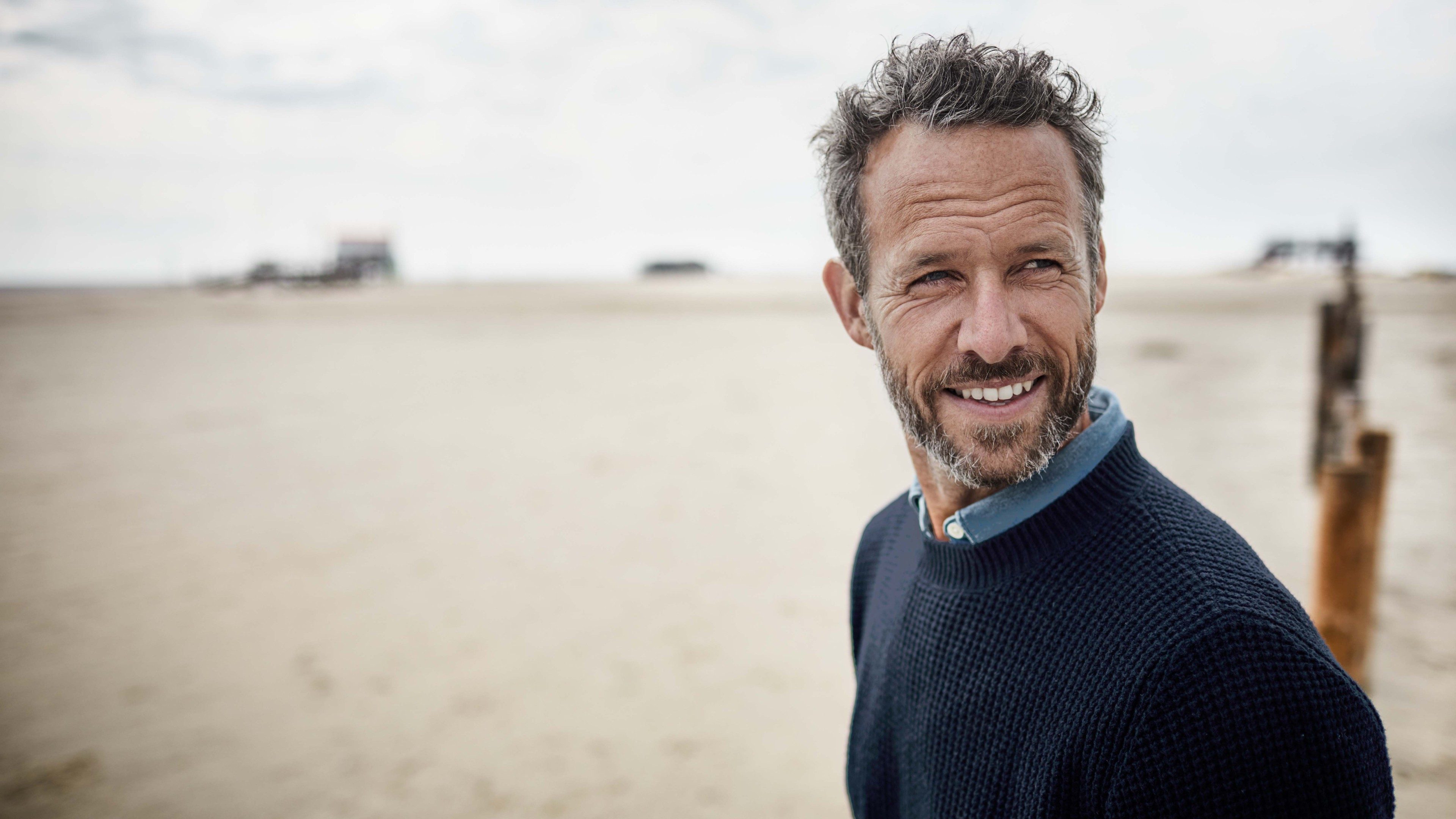 Mann am Strand blickt in die Zukunft und denkt an seine Pensionierung