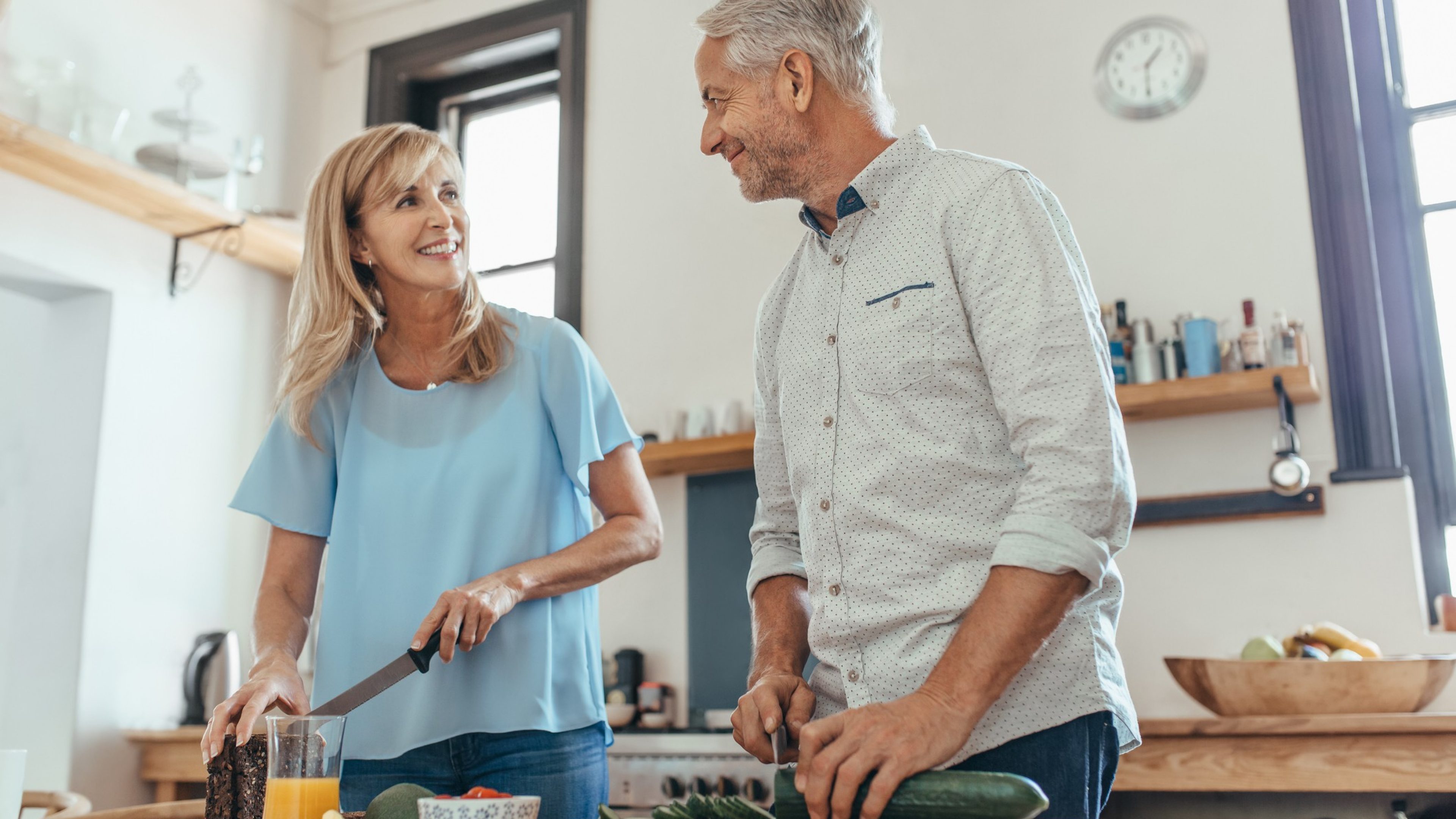 Älteres Ehepaar steht in der Küche ihres Eigenheims und kocht. Sie sind zufrieden und wissen, dass sie mit Ihrer Hypothekenstrategie gut aufgestellt sind.