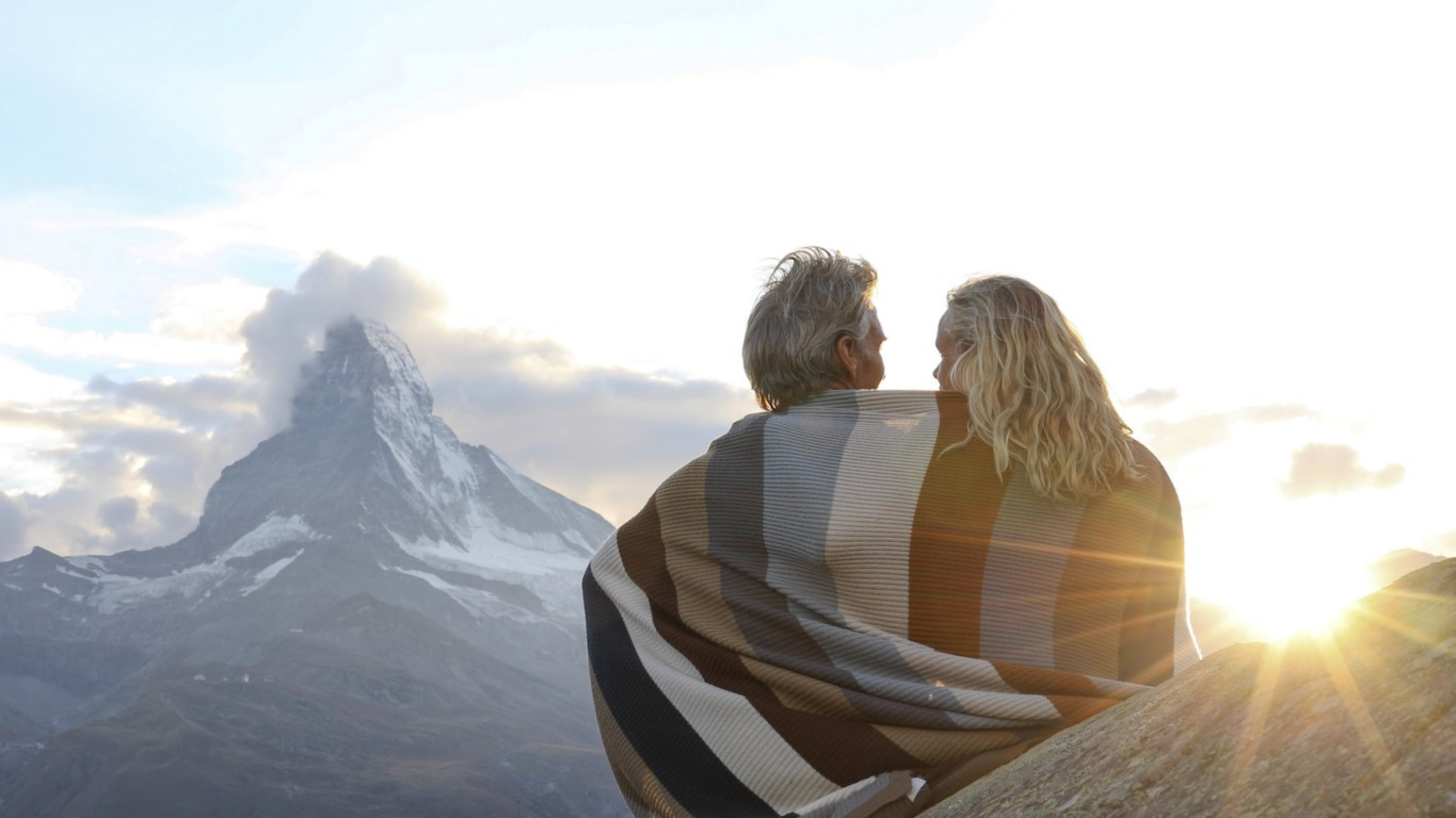Ein Paar sitzt mit einer Decke vor dem Matterhorn. Sie sind zufrieden mit ihrer Strategie "Anlegen wie eine Pensionskasse".