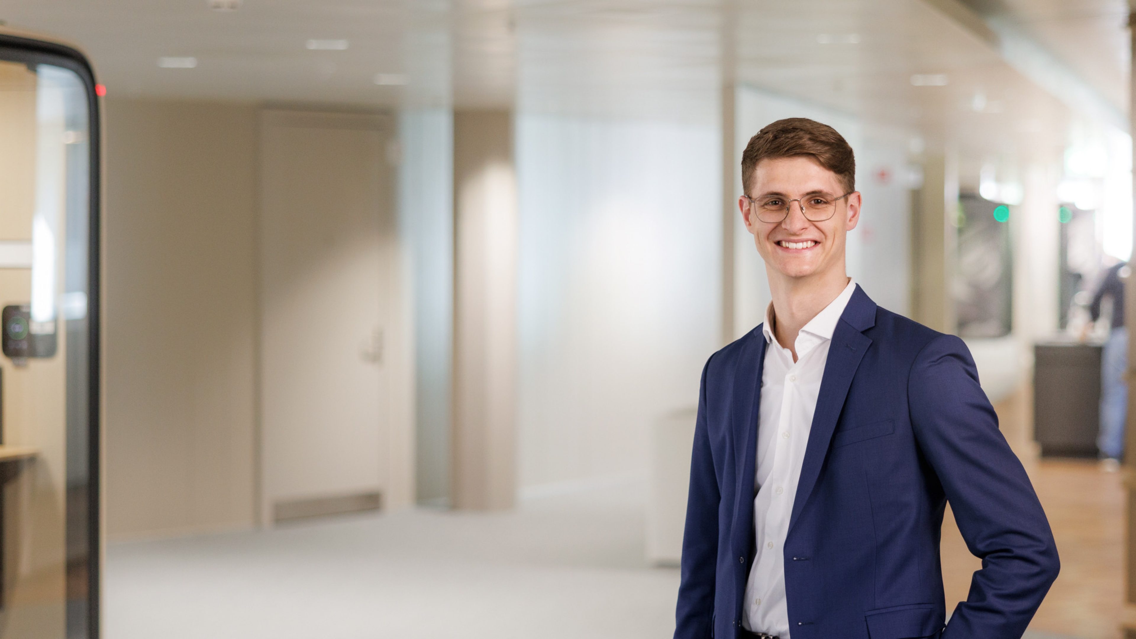 Mitarbeiter steht im lichtdurchfluteten Swiss Life Bürogebäude