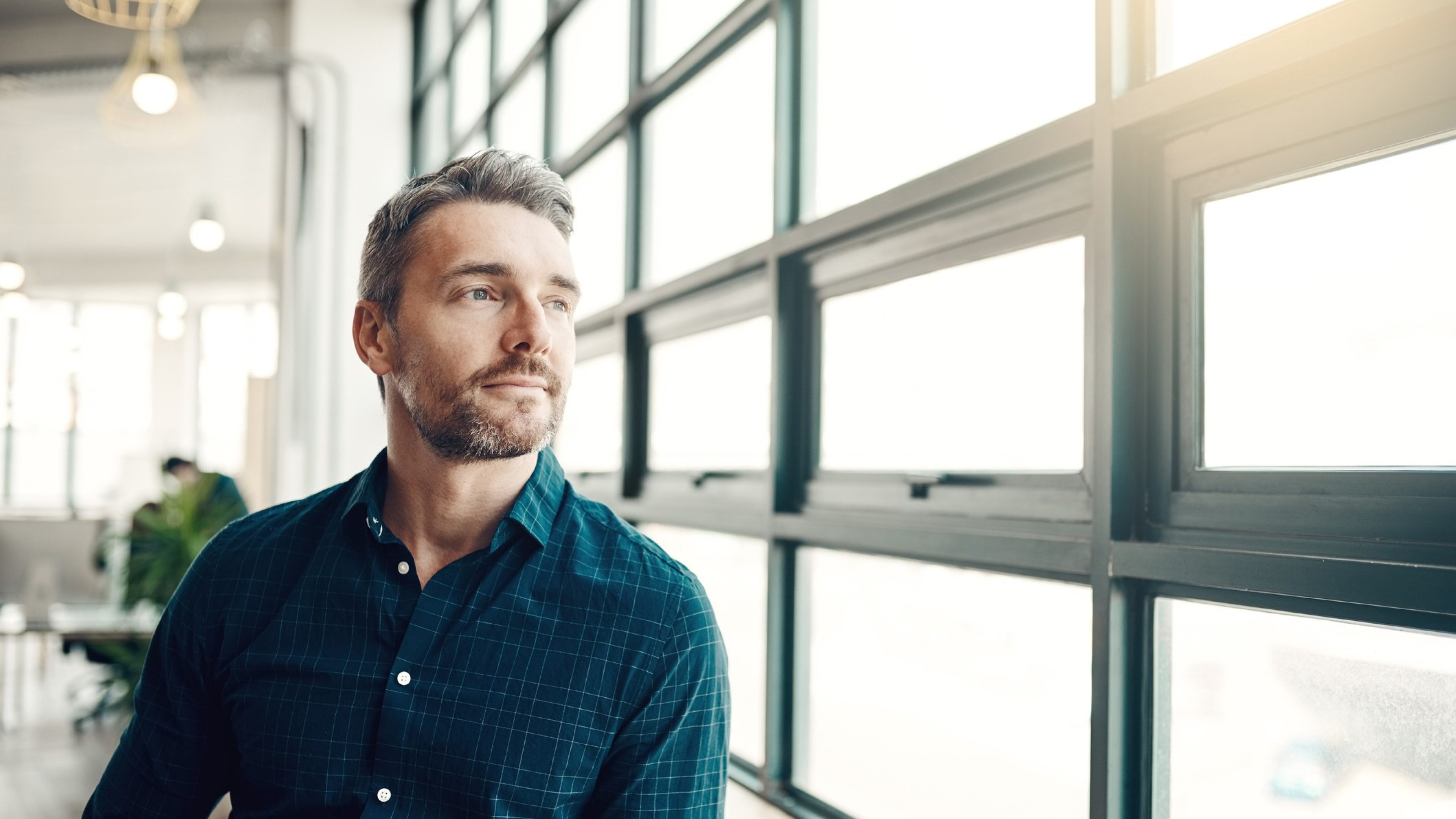 Shot of a mature businessman looking thoughtfully out of an office window